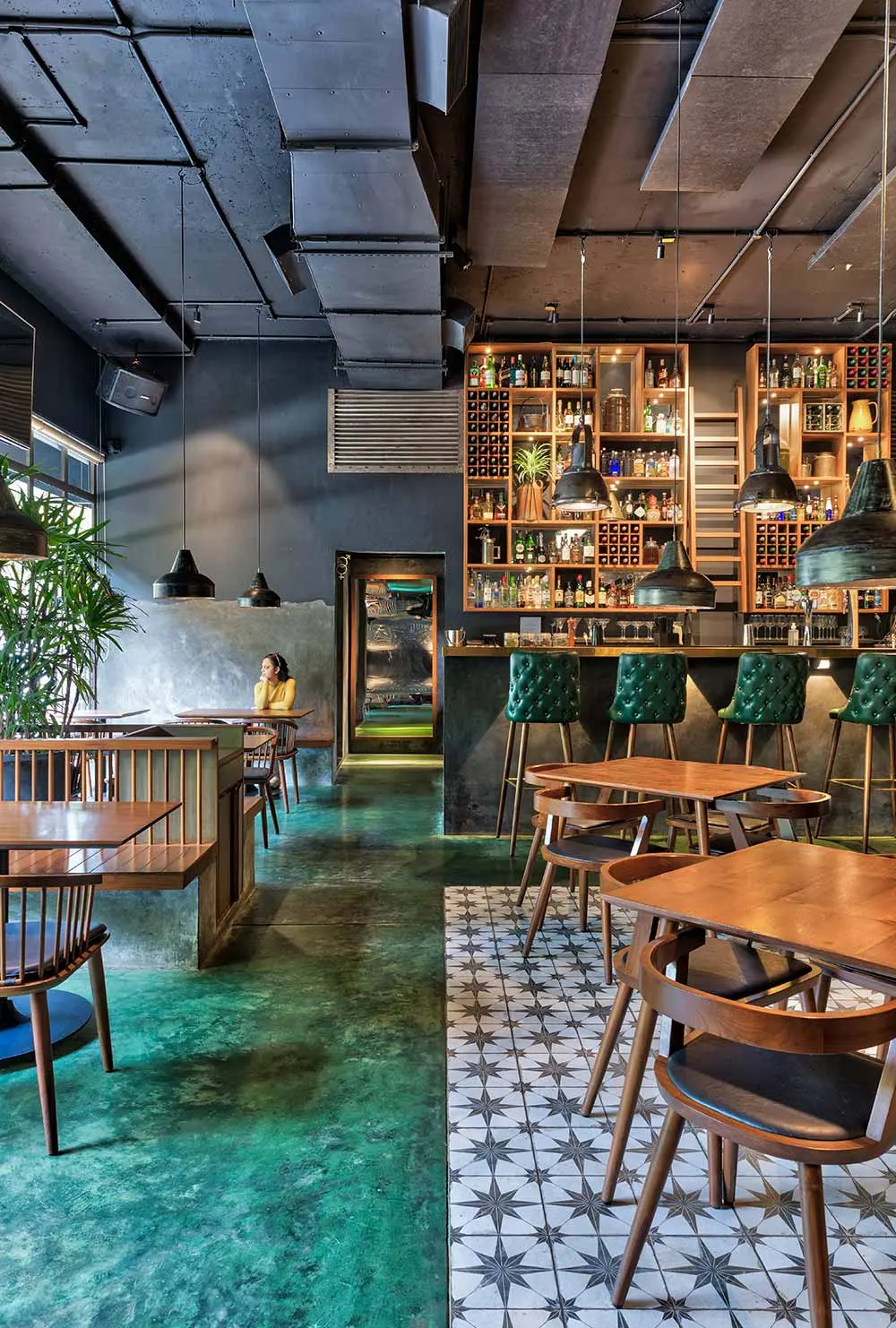 Bar with tall back-bar shelving, green tiled floor and high stools