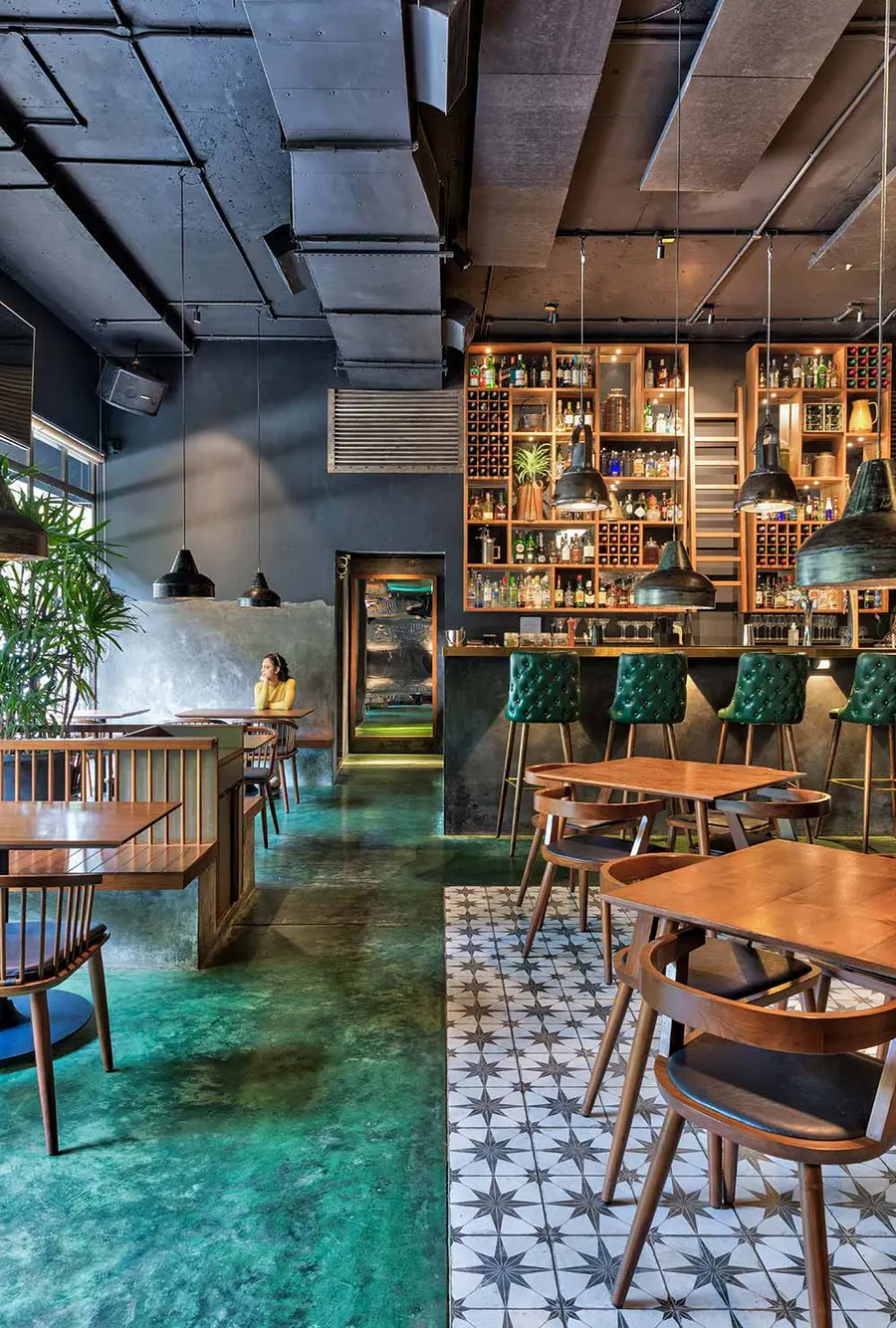 Bar with tall back-bar shelving, green tiled floor and high stools