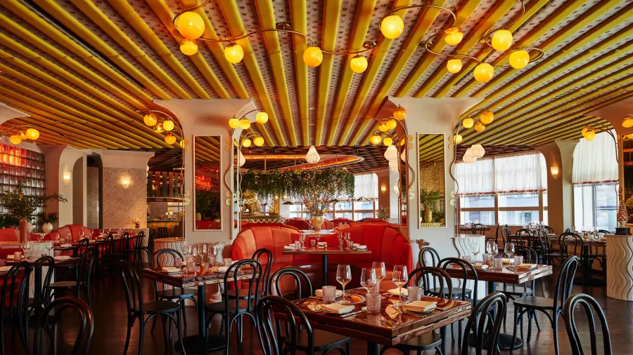 Restaurant with a slatted, lit timber ceiling, red banquettes and bentwood chairs