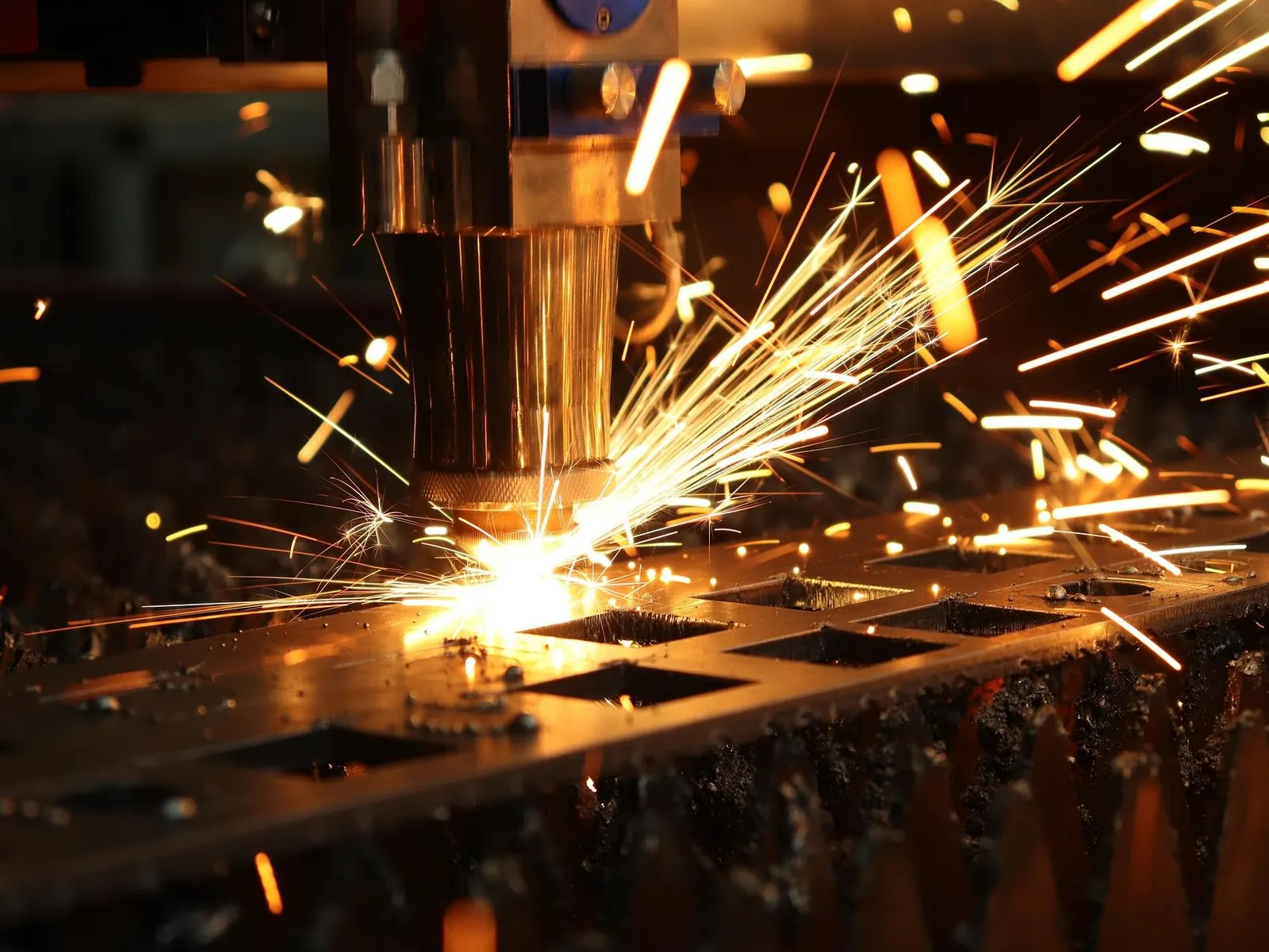 Fibre laser cutting through steel sheet, sparks under the cutting head