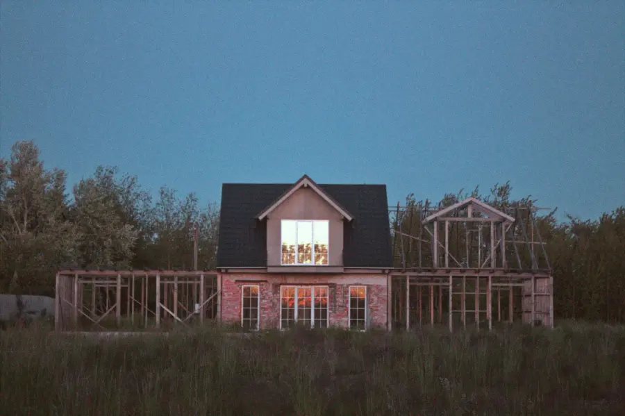 A building under construction at dusk with timber frame visible