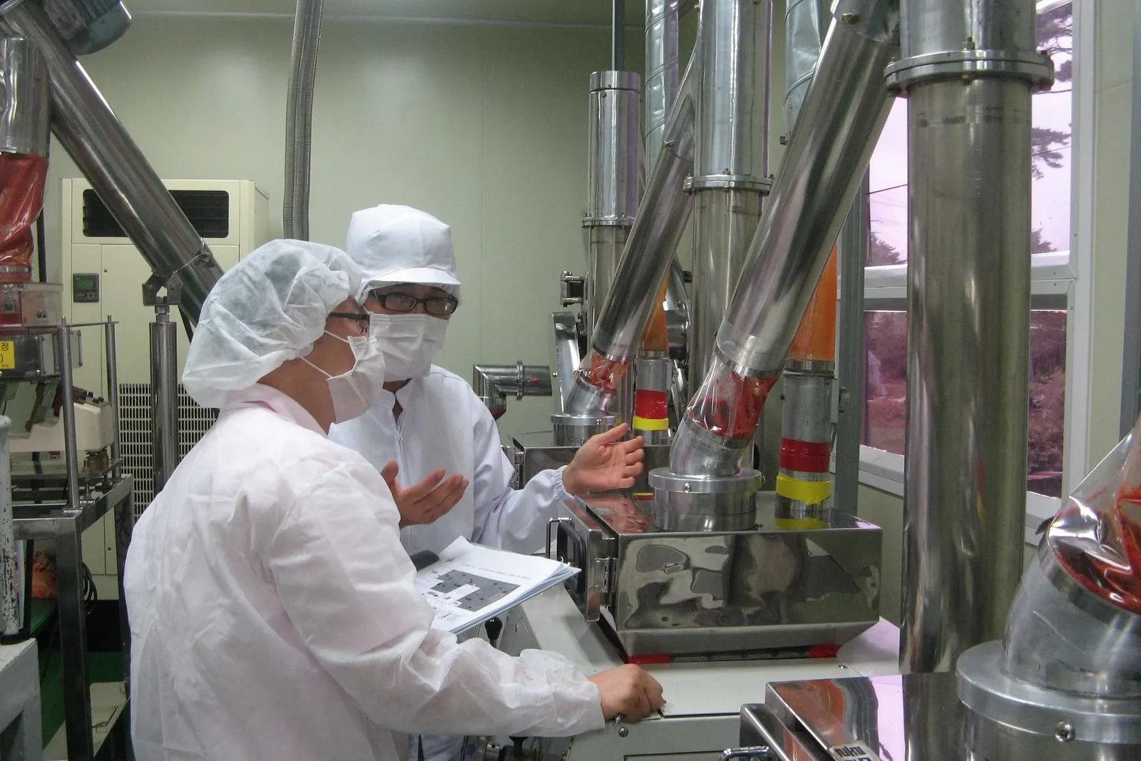 Technicians in hygiene clothing checking stainless process equipment