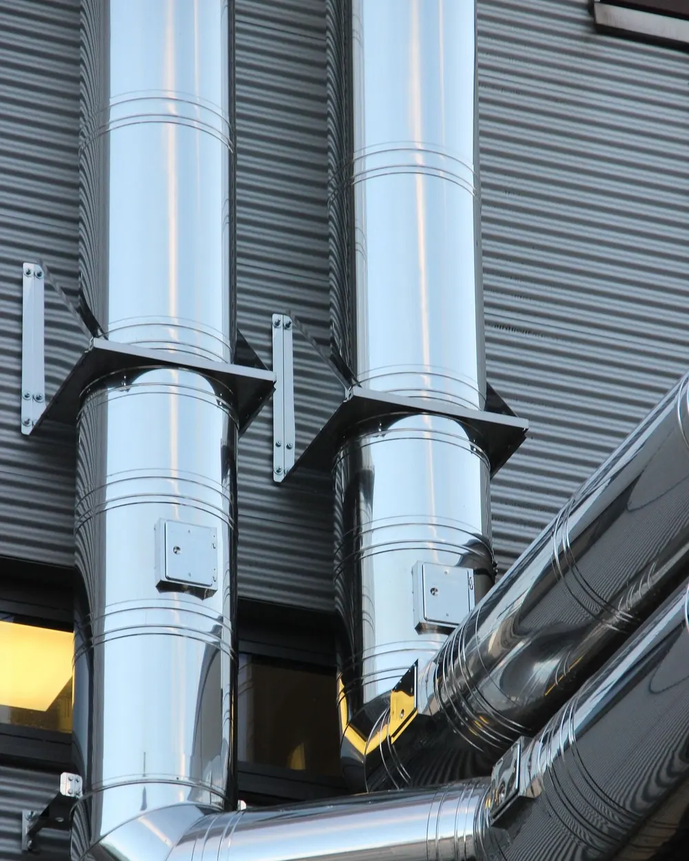 Stainless steel ducts mounted on a metal-clad facade