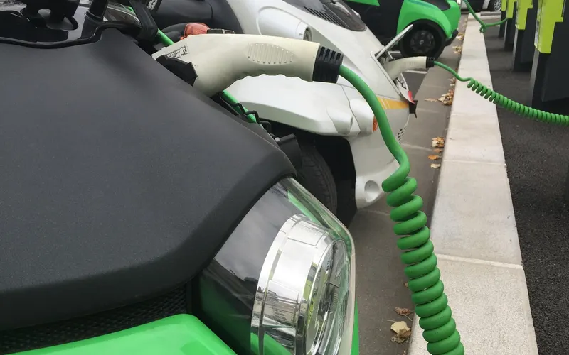 Electric vehicles connected to charging points along a kerb