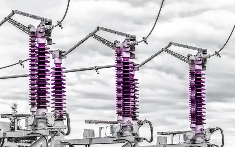 Outdoor high-voltage switchgear with insulators against a cloudy sky