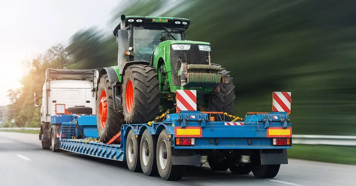 Tractor secured on a blue low-loader trailer on a highway