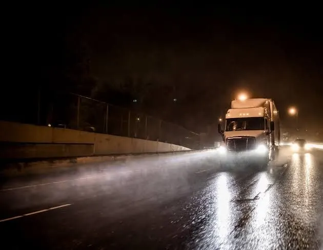 Lorry with headlights on a wet road at night